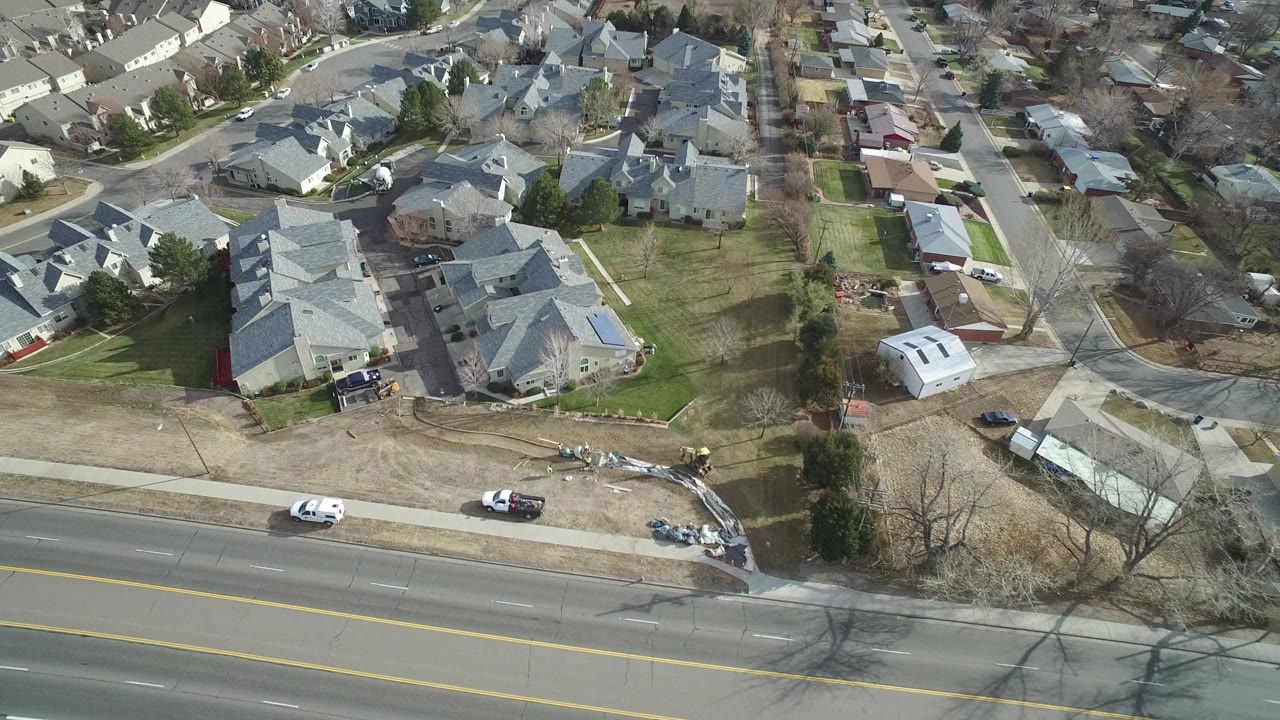 Drone-like view of houses, side streets, lawns, and parked cars.
