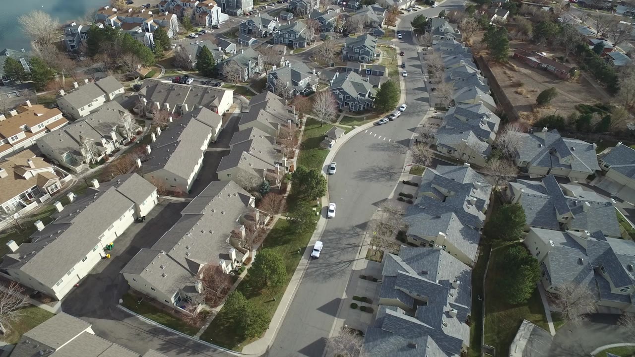 Aerial view of large homes beside curved residential streets and water.