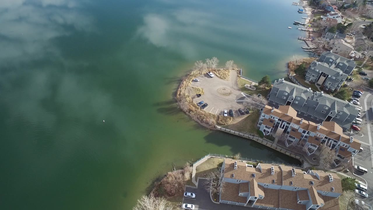 Overhead aerial view of lake water beside townhomes and a curved shoreline.