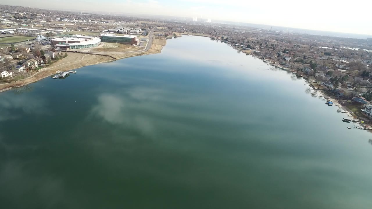 Aerial view over blue-green water beside a suburban shoreline.
