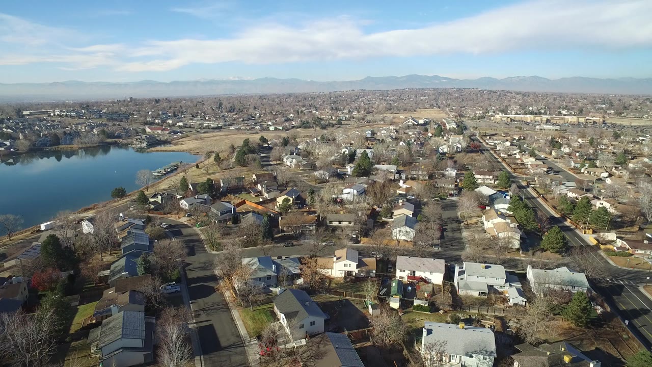 Aerial view of homes, streets, lake, and distant mountains.