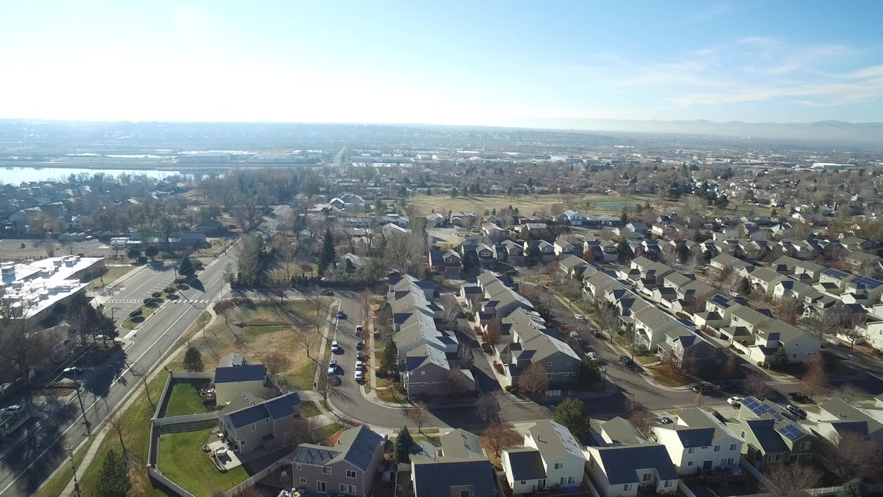 Aerial frame over Hidden Lake, Colorado showing rows of homes, a curving street pattern, open land behind the neighborhood, and no visible people.