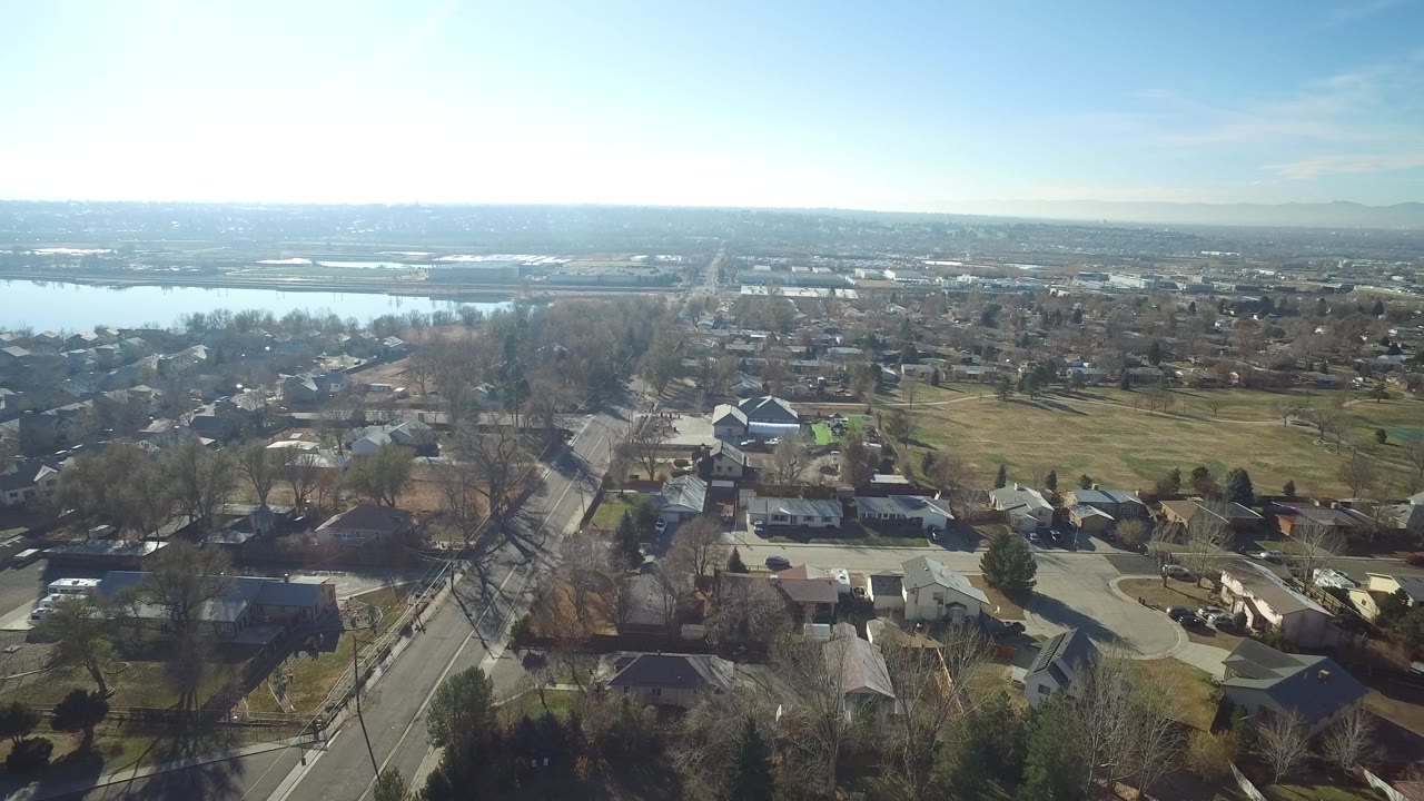 At 0:01, the Hidden Lake aerial holds on a diagonal residential road, clustered homes, bare trees, open grass, distant lake water, and no visible people.