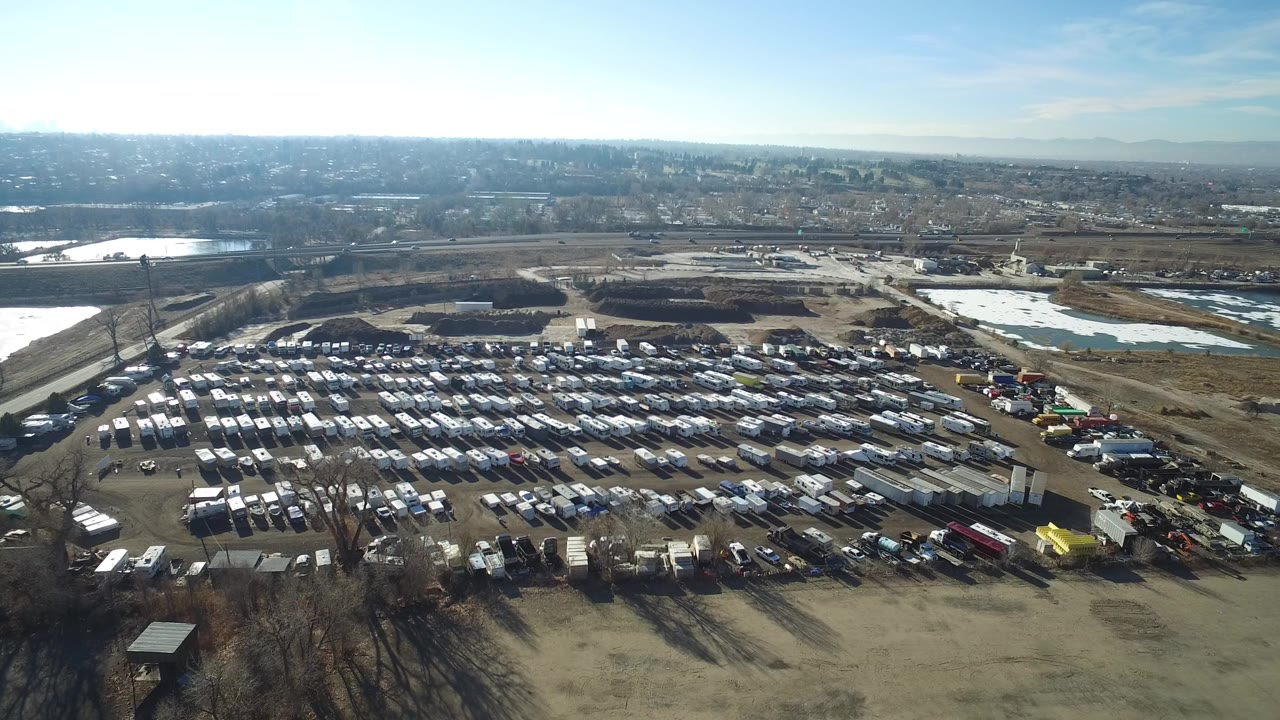 Aerial view of a large vehicle lot beside open land and water