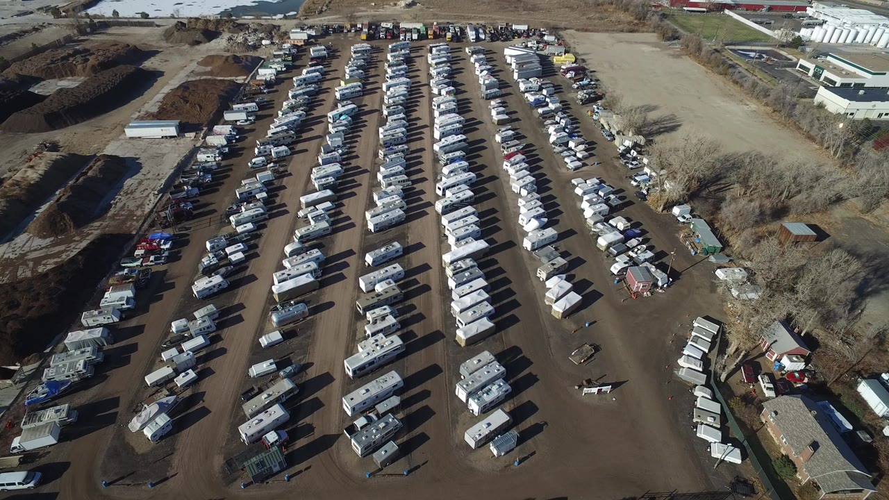 Overhead view of rows of parked RVs and vehicles on dirt lanes.