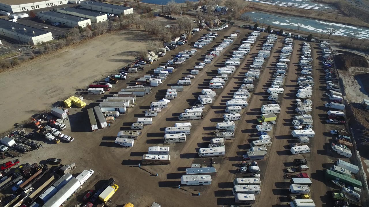 Aerial view of rows of parked RVs and vehicles in a dirt industrial lot.