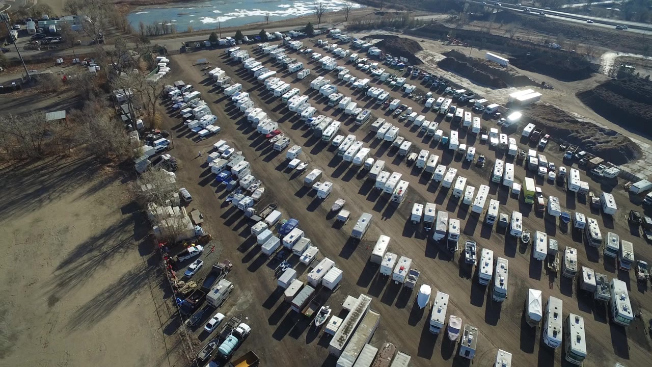 A second overhead view shows the Hidden Lake, Colorado vehicle lot from a similar angle, with bright roof glare on several trailers and no visible people.