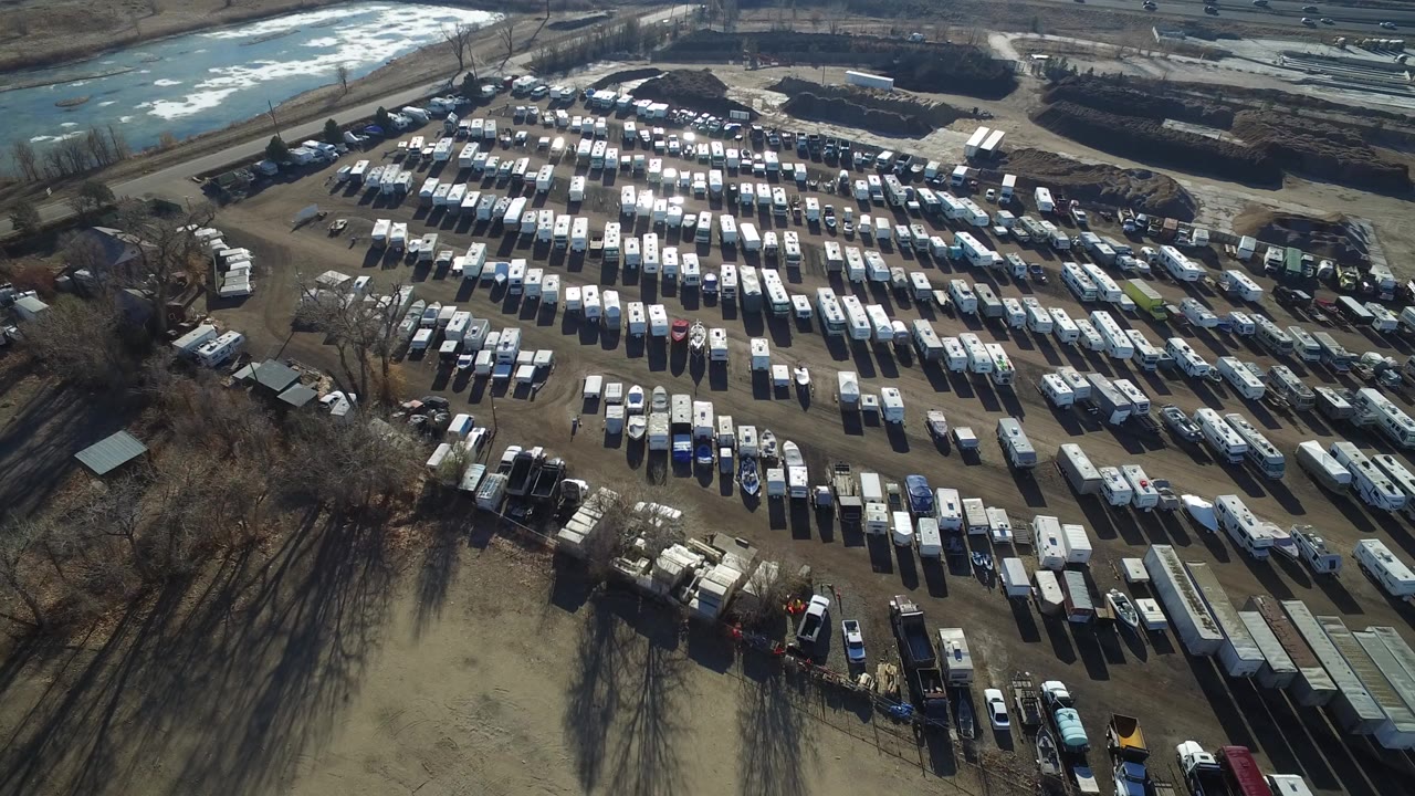 Aerial view of a large dirt parking lot filled with rows of vehicles.