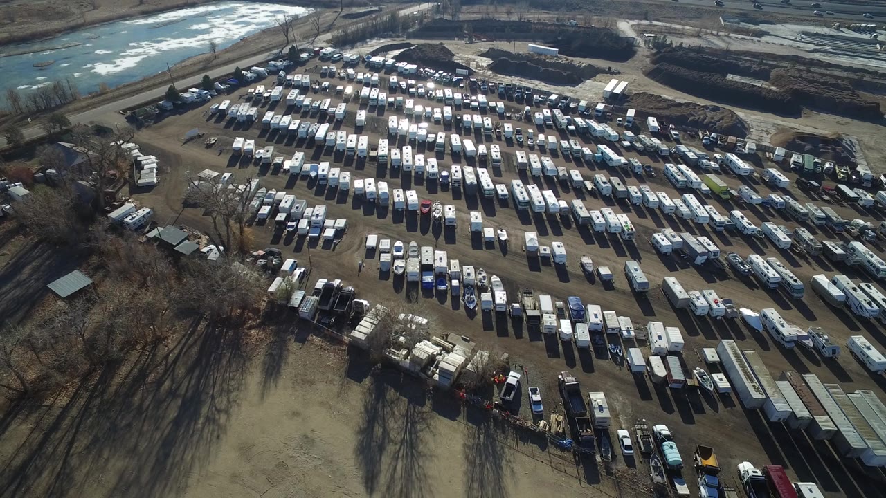 Aerial view in Hidden Lake, Colorado, looking across dense rows of parked vehicles toward roads and pale ground patches, with no visible people.