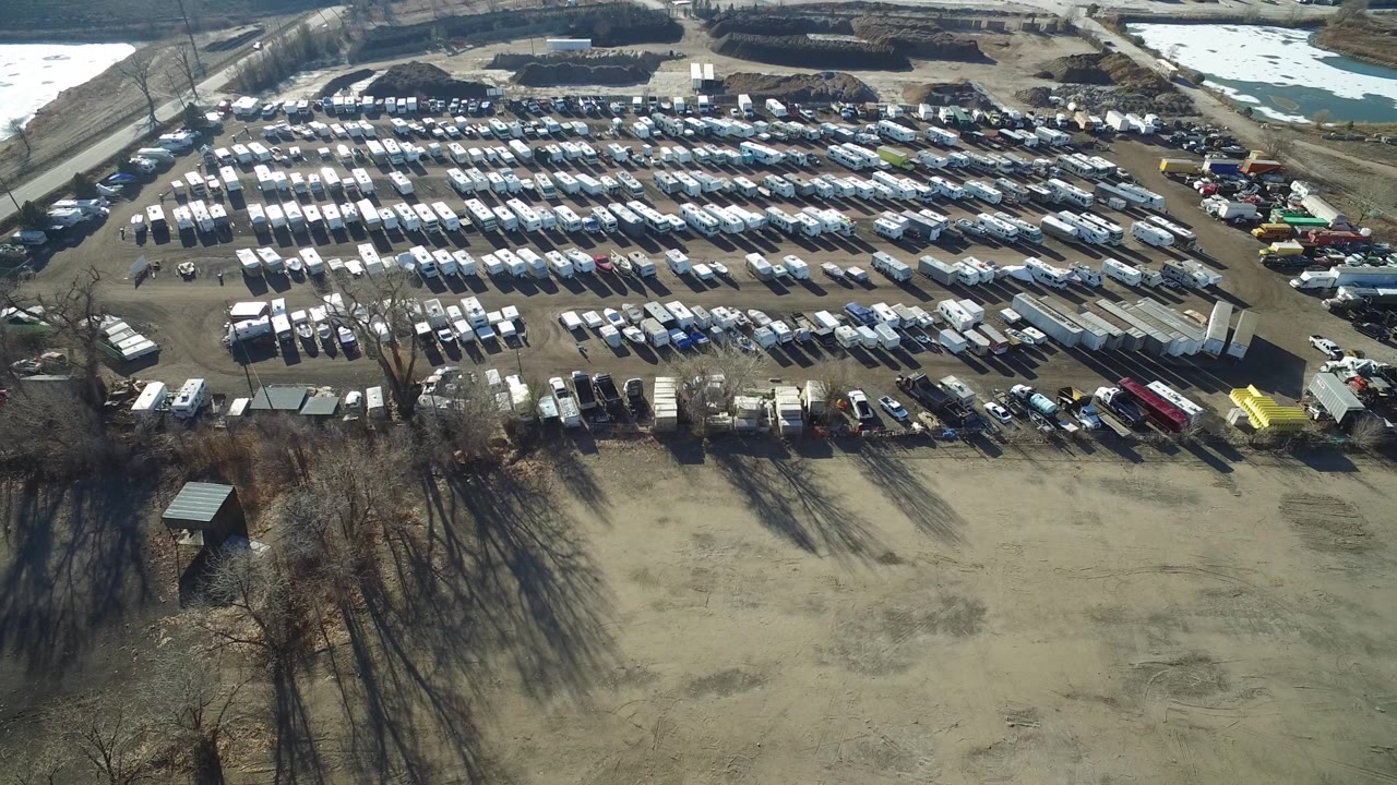 One second in, the Hidden Lake aerial view keeps the packed rows of cars, trucks, and trailers centered above a broad tan field, with no visible people.