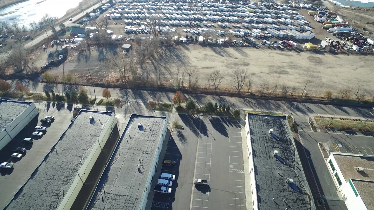 Drone view over flat-roof industrial buildings and parking lots.