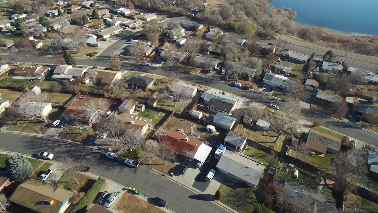 Oblique aerial view over Hidden Lake, Colorado houses and residential streets, with a blue lake at the top of frame and no visible people.