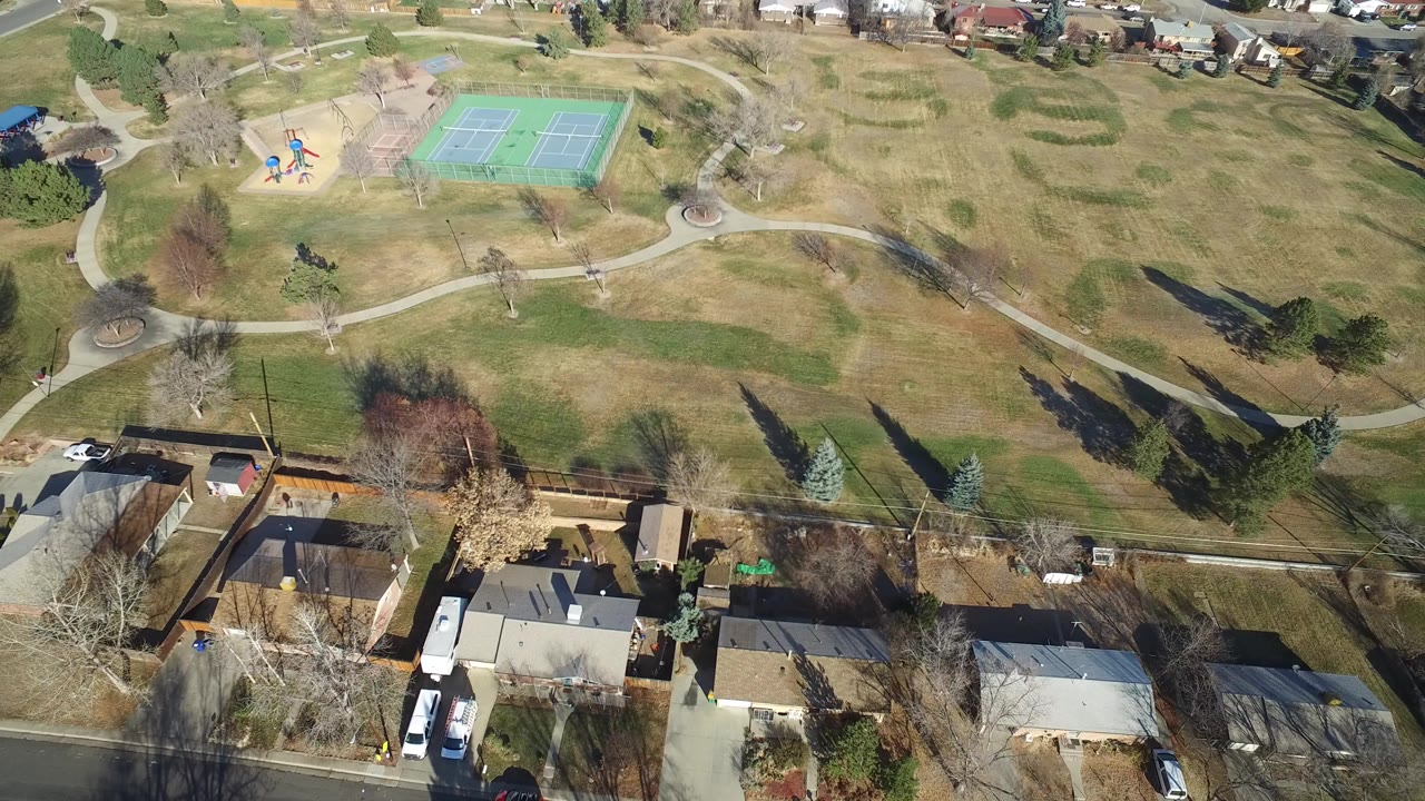 Aerial view of homes beside a park with tennis courts and curved paths.