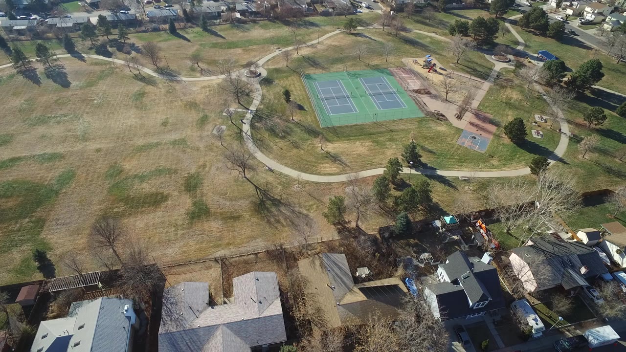 Aerial view of a suburban park with tennis courts and nearby homes.