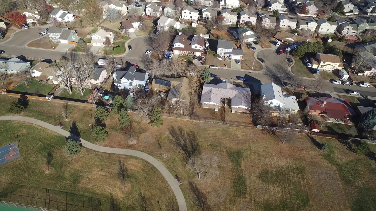 Aerial view of houses beside open grass and a curving path.