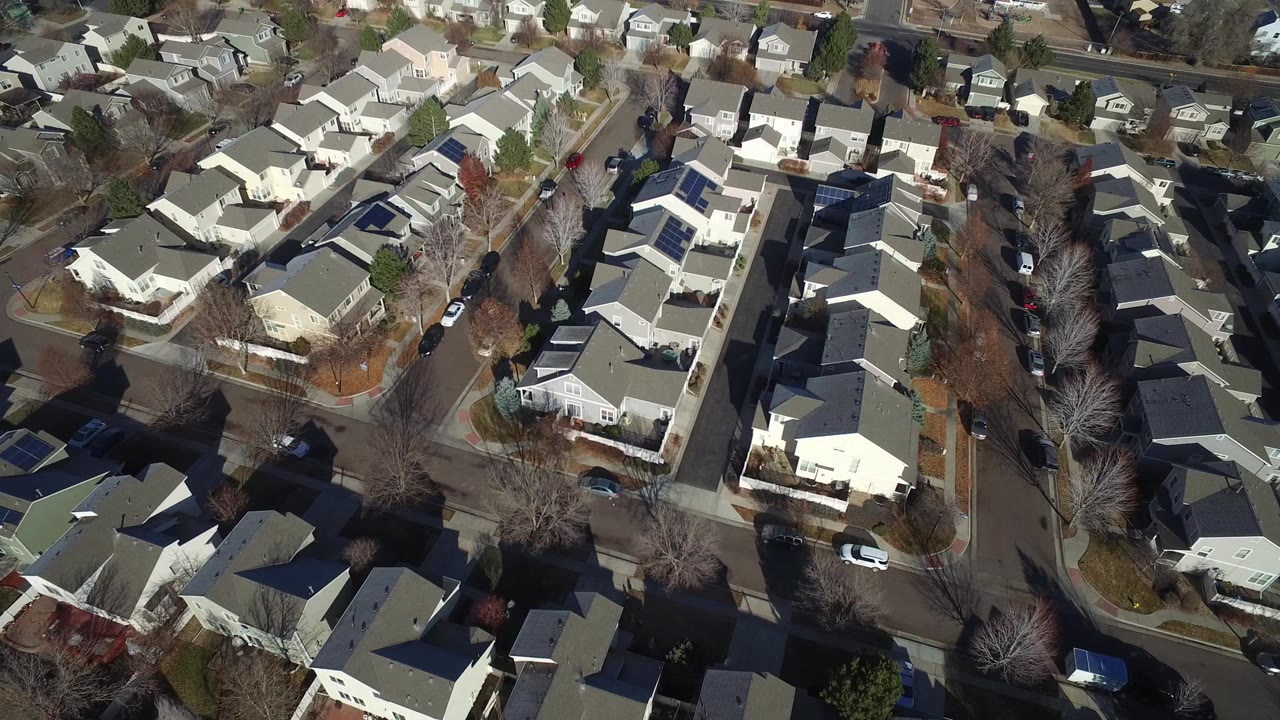 Aerial view in Hidden Lake, Colorado with tightly spaced houses, long tree shadows, parked cars beside the curbs, and no clearly visible people.