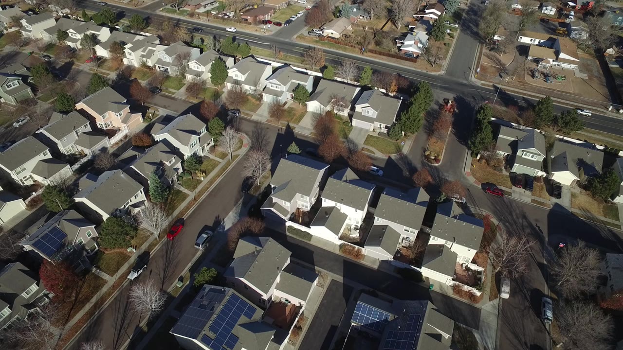Aerial frame in Hidden Lake, Colorado showing light-colored rooftops, fenced backyards, bare trees, and cars on the surrounding residential roads, with no visible people.
