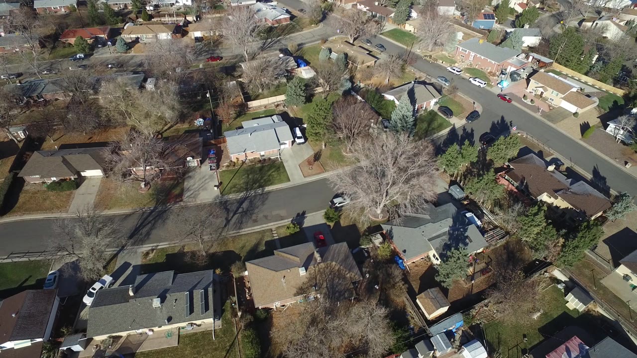 Aerial frame over Hidden Lake, Colorado with a curved residential road, light-colored roofs, driveways, fenced yards, leafless trees, and no visible people.