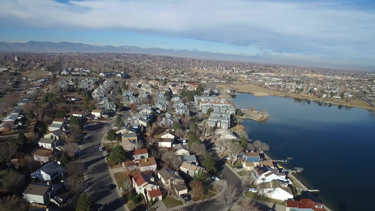 Aerial view of lakeside houses and a blue lake under a partly cloudy sky.