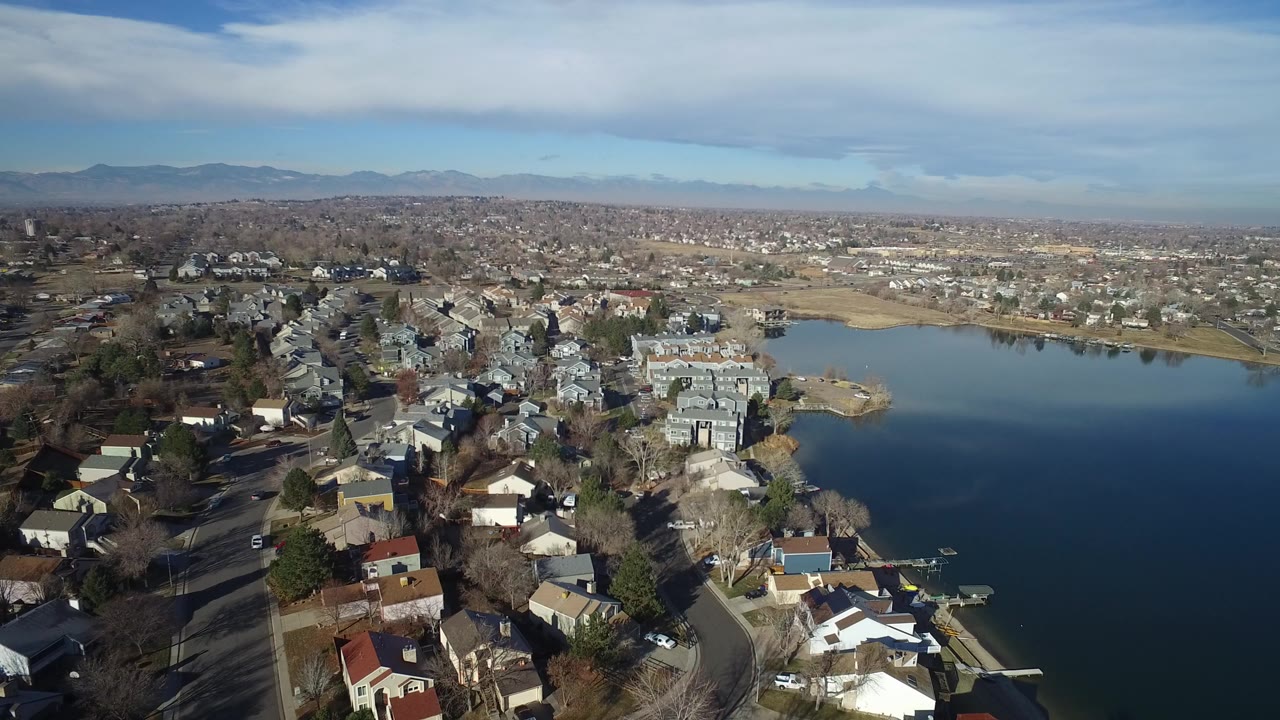 Aerial view of lakeside homes, suburban streets, and distant mountains.