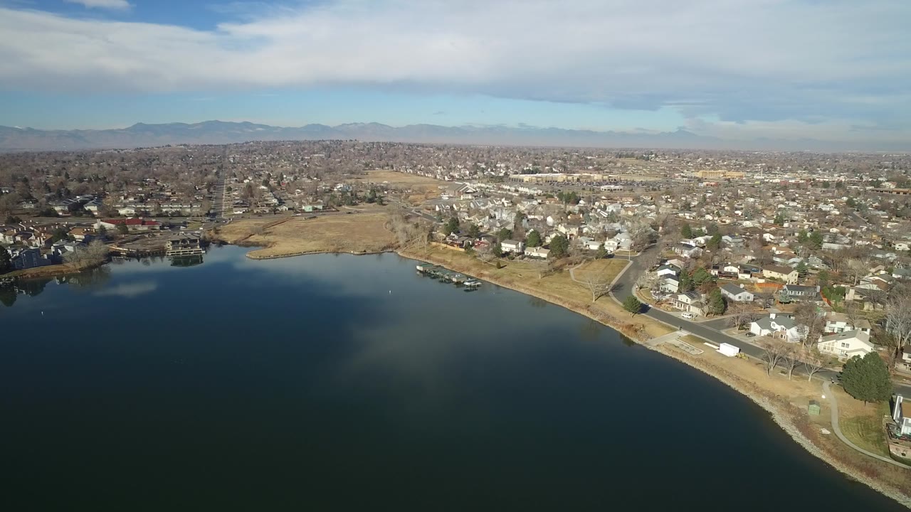 Aerial view in Hidden Lake, Colorado, showing the lake edge, several docks, small boats near shore, a residential grid, tan open ground, and no visible people.