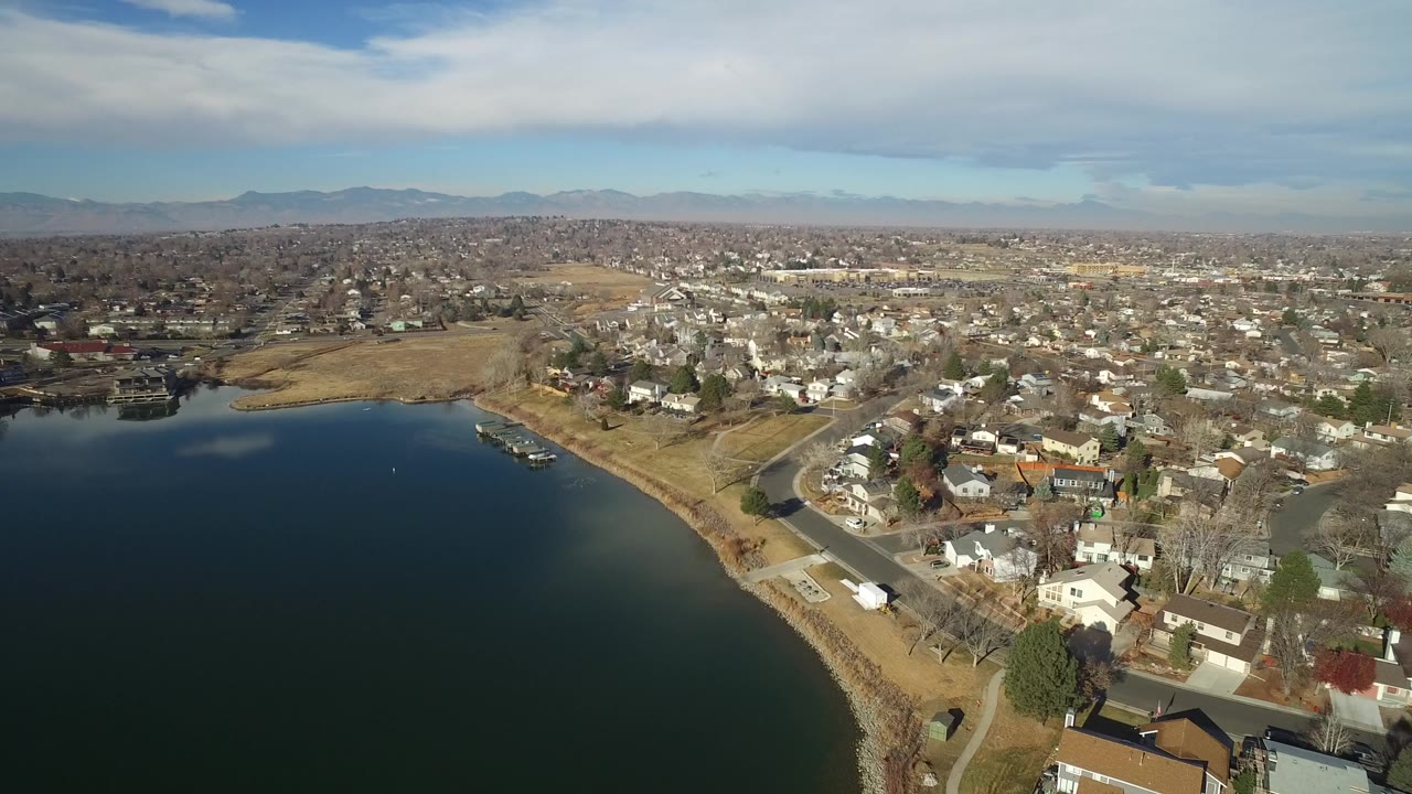 Aerial view of a lake beside suburban homes and roads.