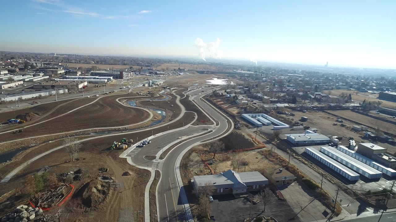 Aerial view of curving new roads through graded lots near buildings.