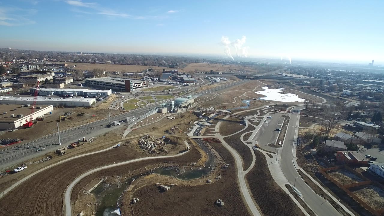 High aerial view of roads, paths, open earth, buildings, and snow patches.