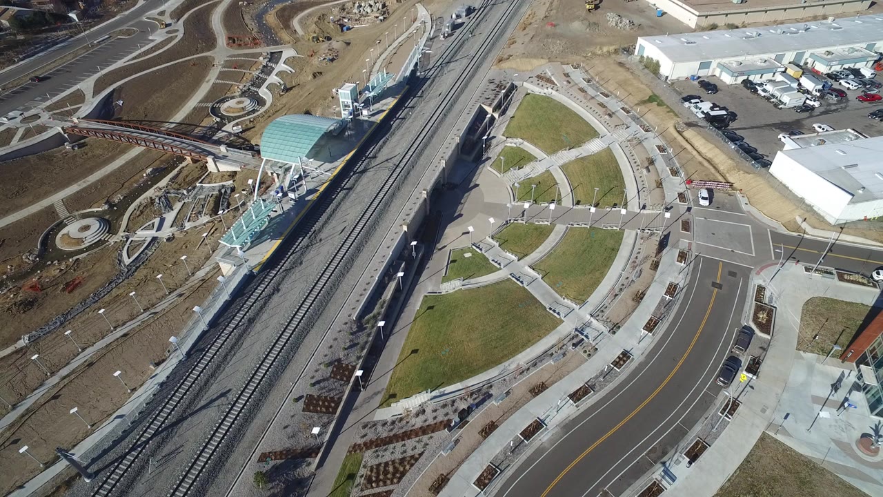 Aerial view of rail tracks beside a curved roadway and pedestrian plaza.