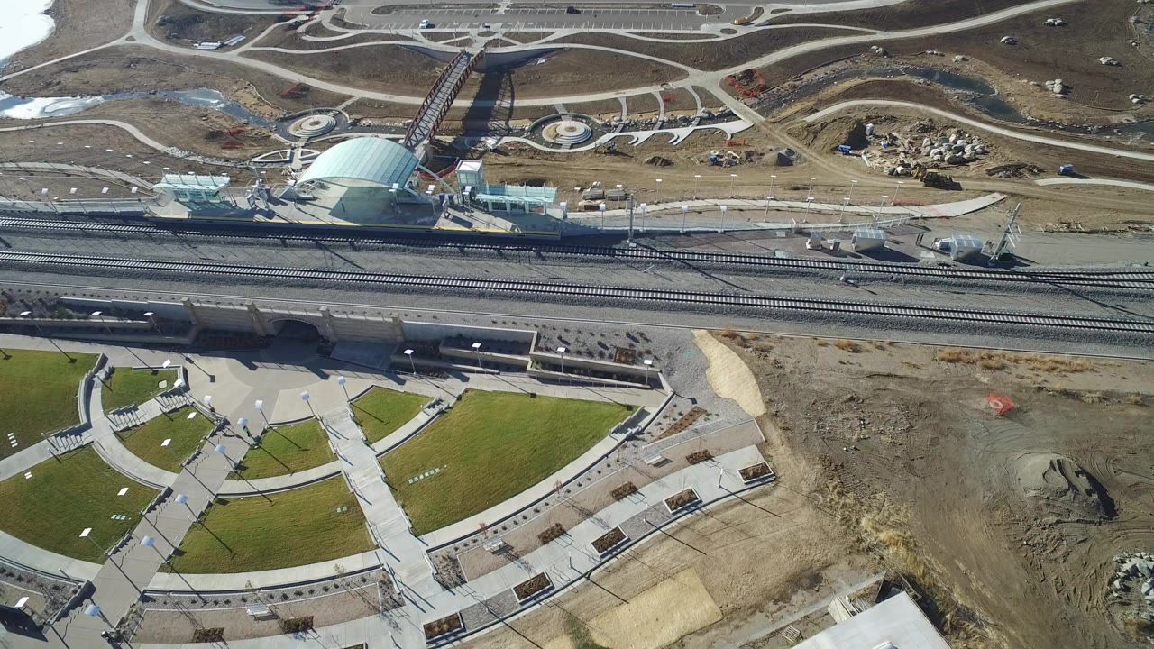 Aerial view of a semi-circular green lawn beside roads and rail tracks.