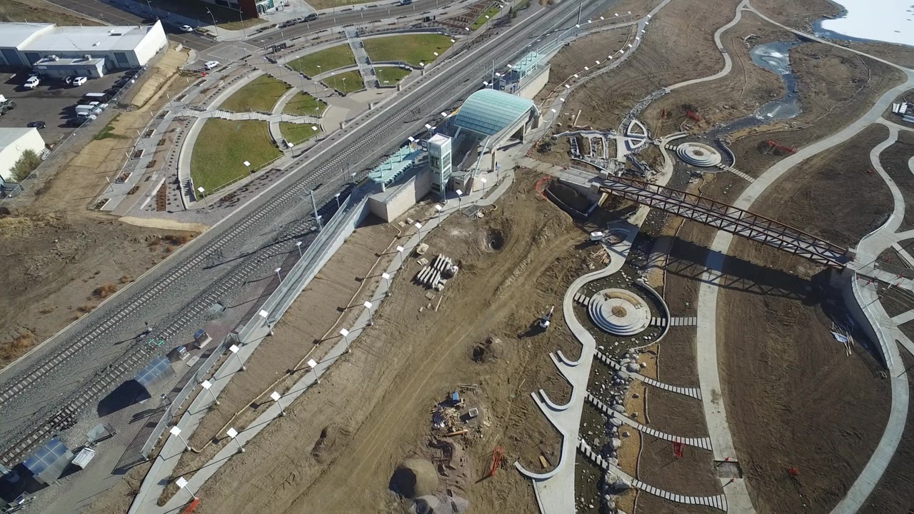Overhead view of station-like structure, rail tracks, paths, and brown terrain.
