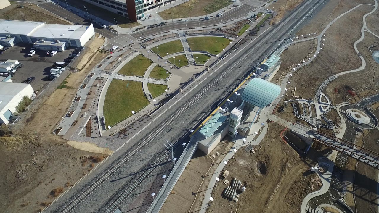 Overhead Hidden Lake, Colorado frame with the rail corridor running diagonally past a curved road network, green lawn panels, white buildings, parked vehicles, and no visible people.