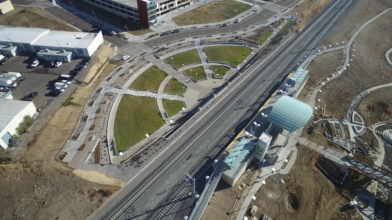 Top-down town view with tracks, a covered walkway, parking, and buildings.