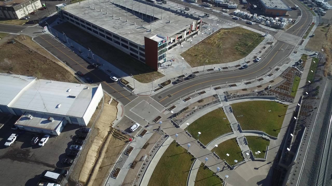 Overhead view of a parking garage beside roads and a white-roofed building.