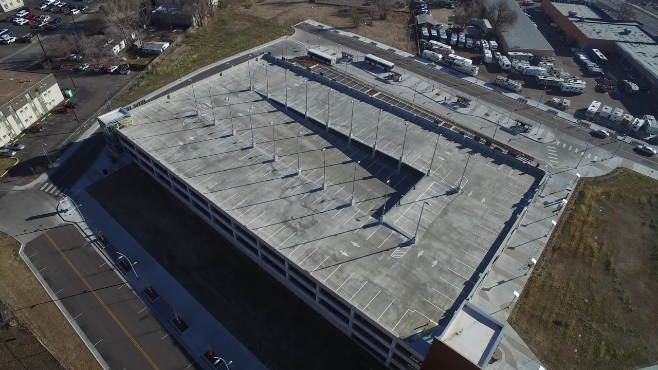 Aerial view of a concrete parking garage beside roads and industrial buildings.