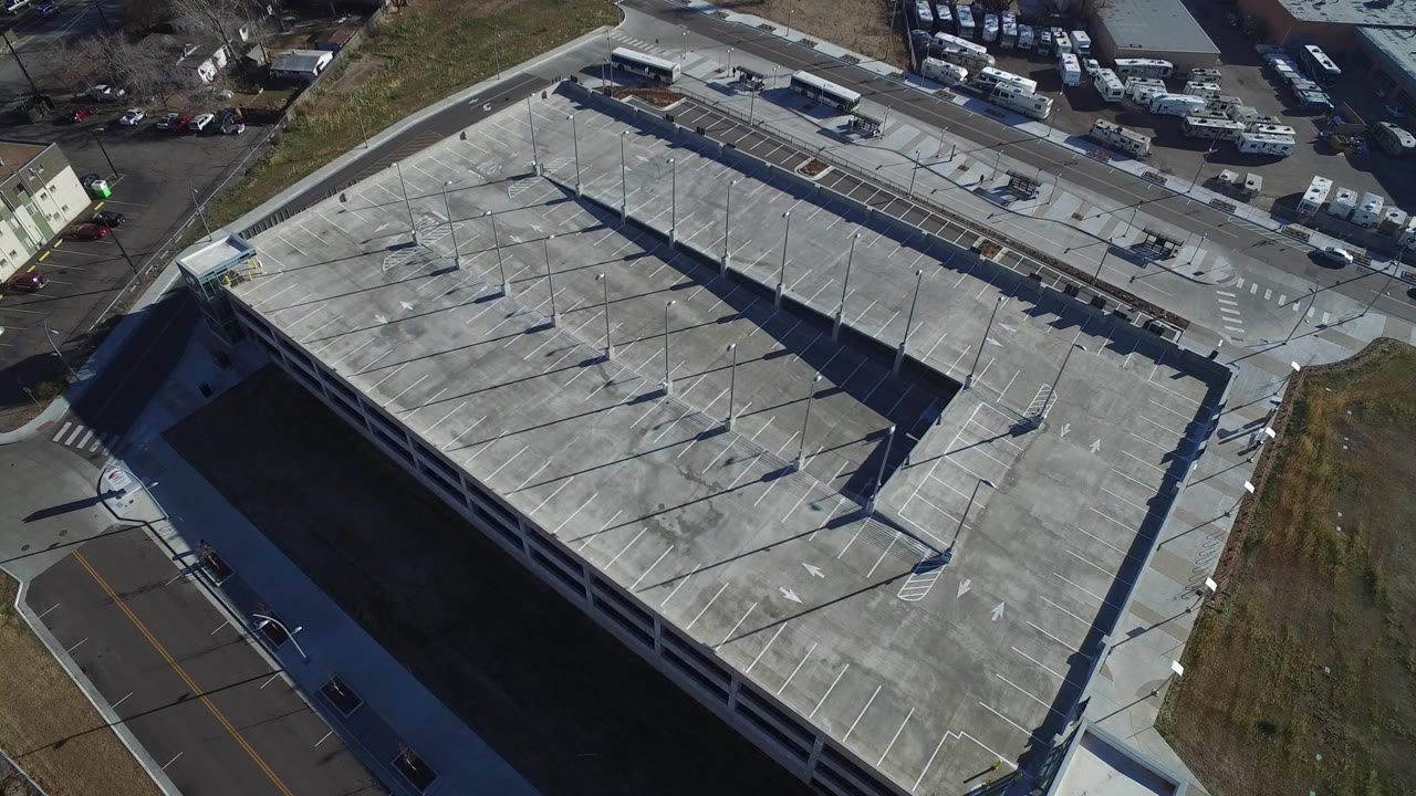 Aerial view of a large concrete parking structure beside roads and grass lots.