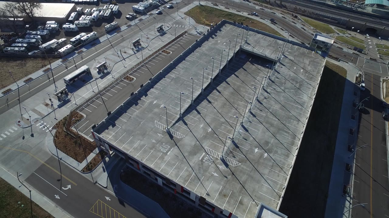 High aerial view of a large concrete-roofed facility beside roads and parking areas.