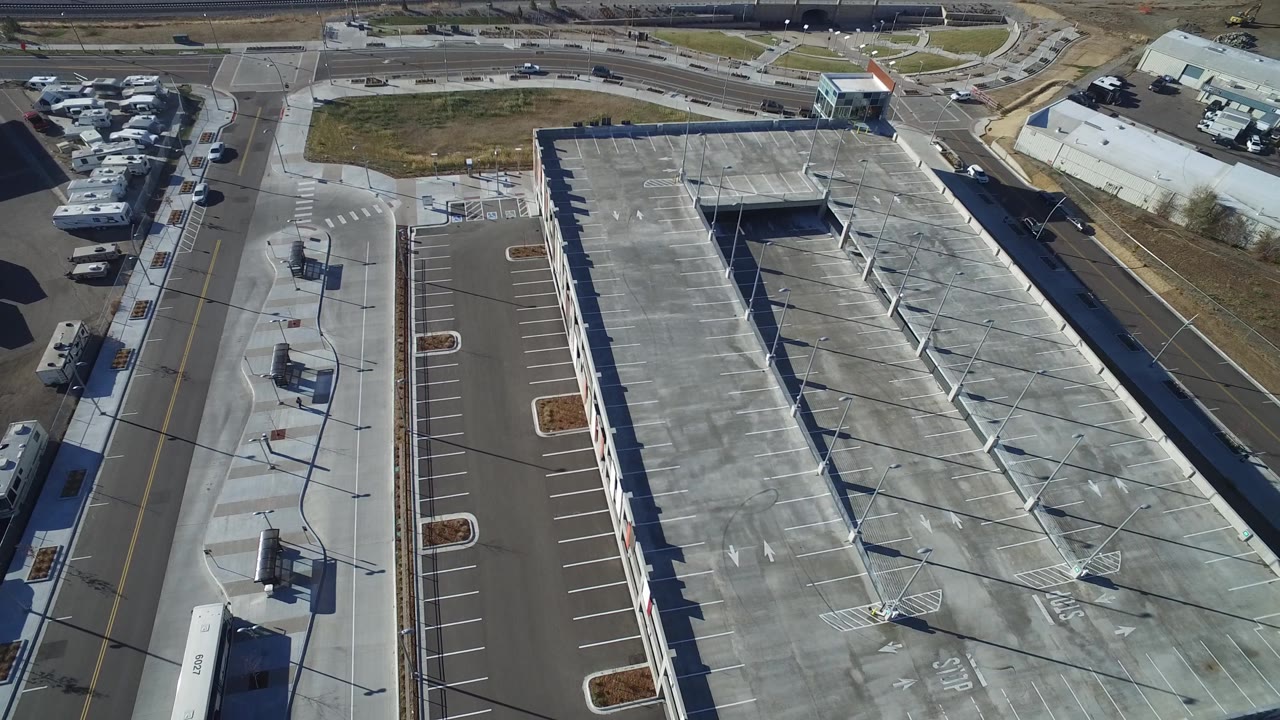 Second aerial frame of the Hidden Lake warehouse, showing the roof from above with parking rows on one side, a road intersection nearby, and no visible people.