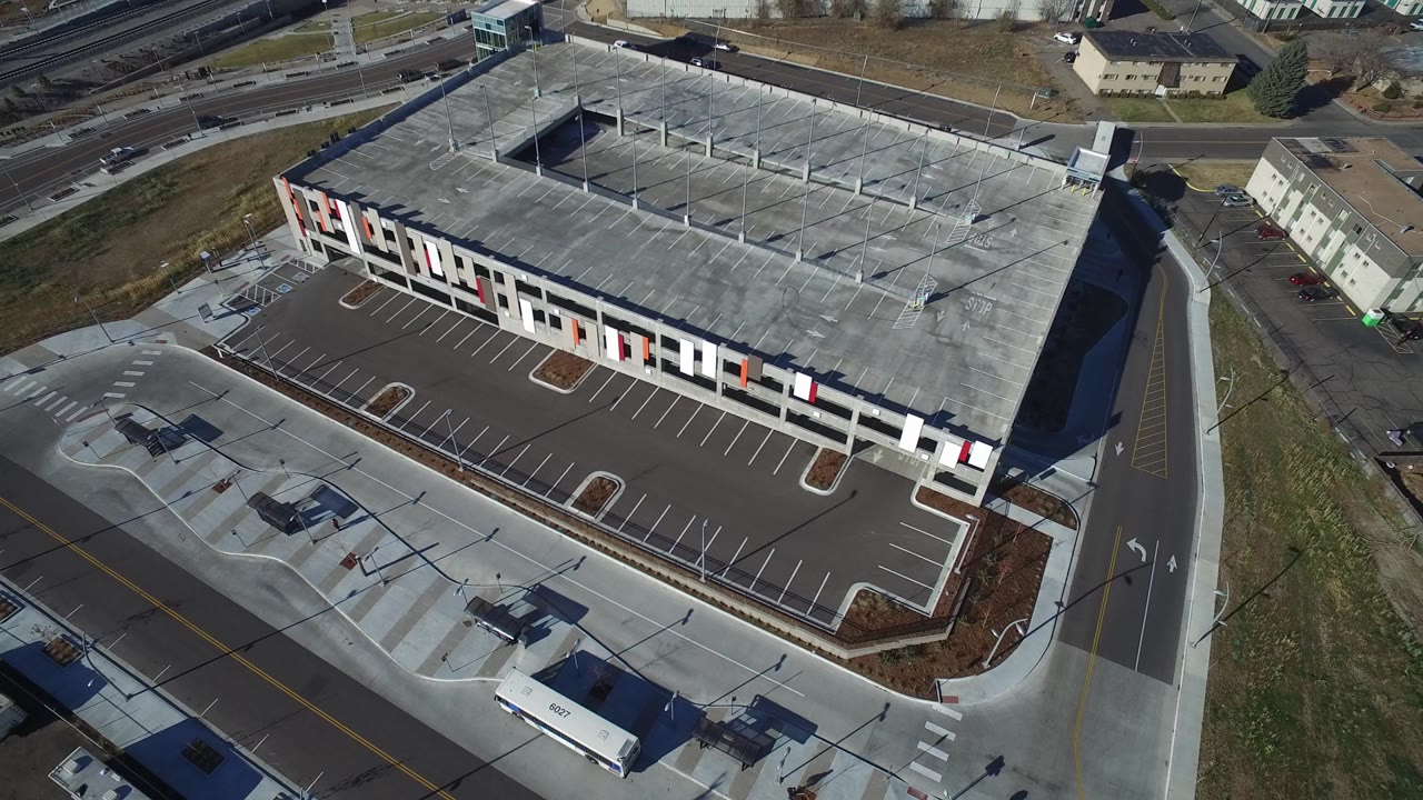 Aerial view of a large flat-roofed building and marked parking lot.