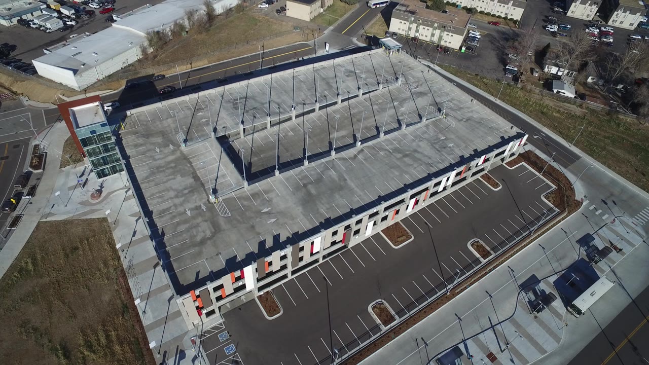 Aerial view of a modern shopping center with an empty parking lot and roof deck.