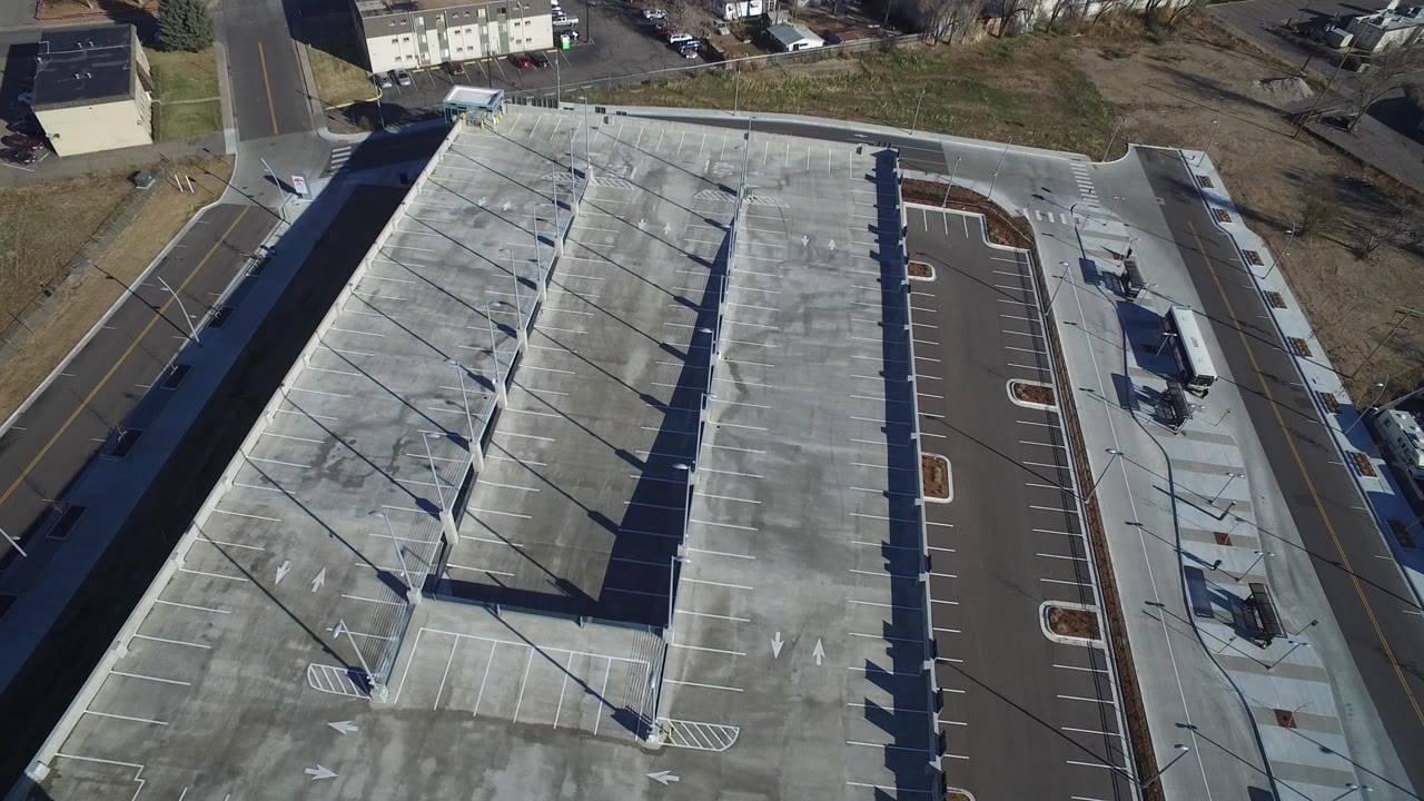 Overhead view of a large gray facility beside roads and parking lanes.