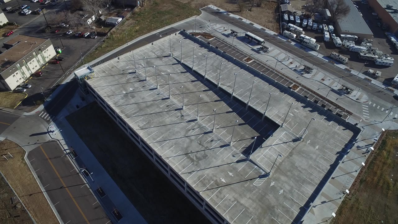 Aerial view over a large gray concrete parking structure and nearby roads.