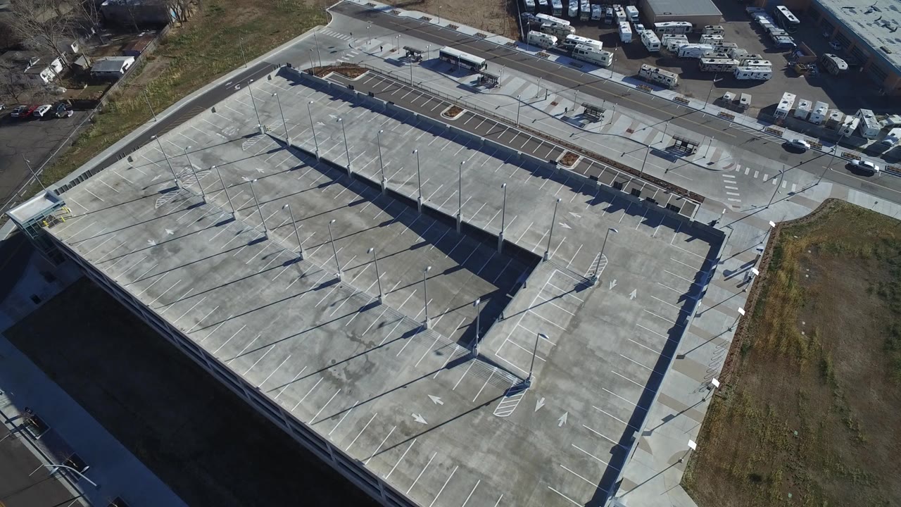 First frame of the Hidden Lake, Colorado clip shows a high overhead view of a mostly empty concrete parking garage, access road, nearby RVs, and no visible people.