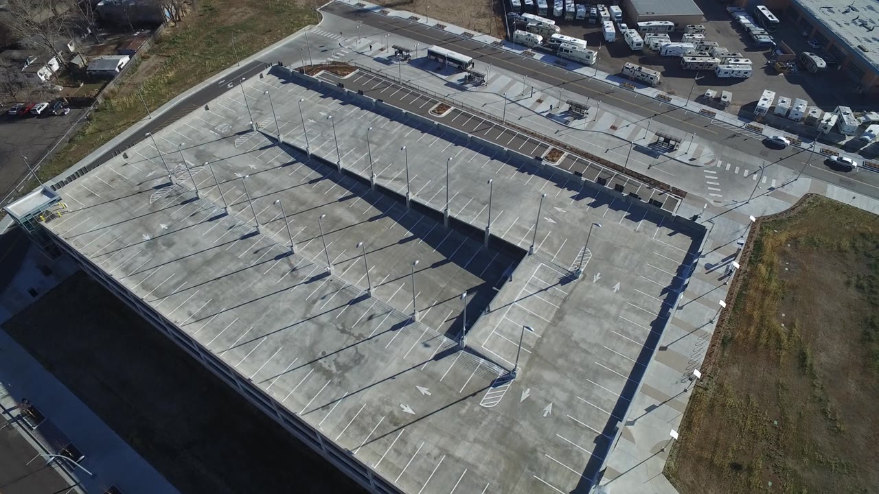 At 0:01, the Hidden Lake, Colorado aerial holds above the parking garage, with light poles casting long shadows and RVs visible near the building, with no visible people.