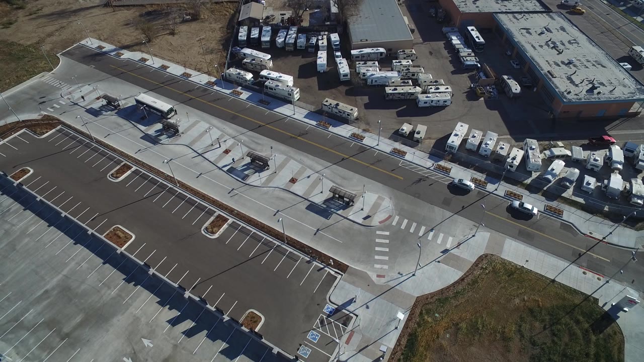High overhead frame of a Hidden Lake, Colorado industrial area with empty parking stalls, crosswalks, warehouse roofs, parked trailers, cars, and no visible people.