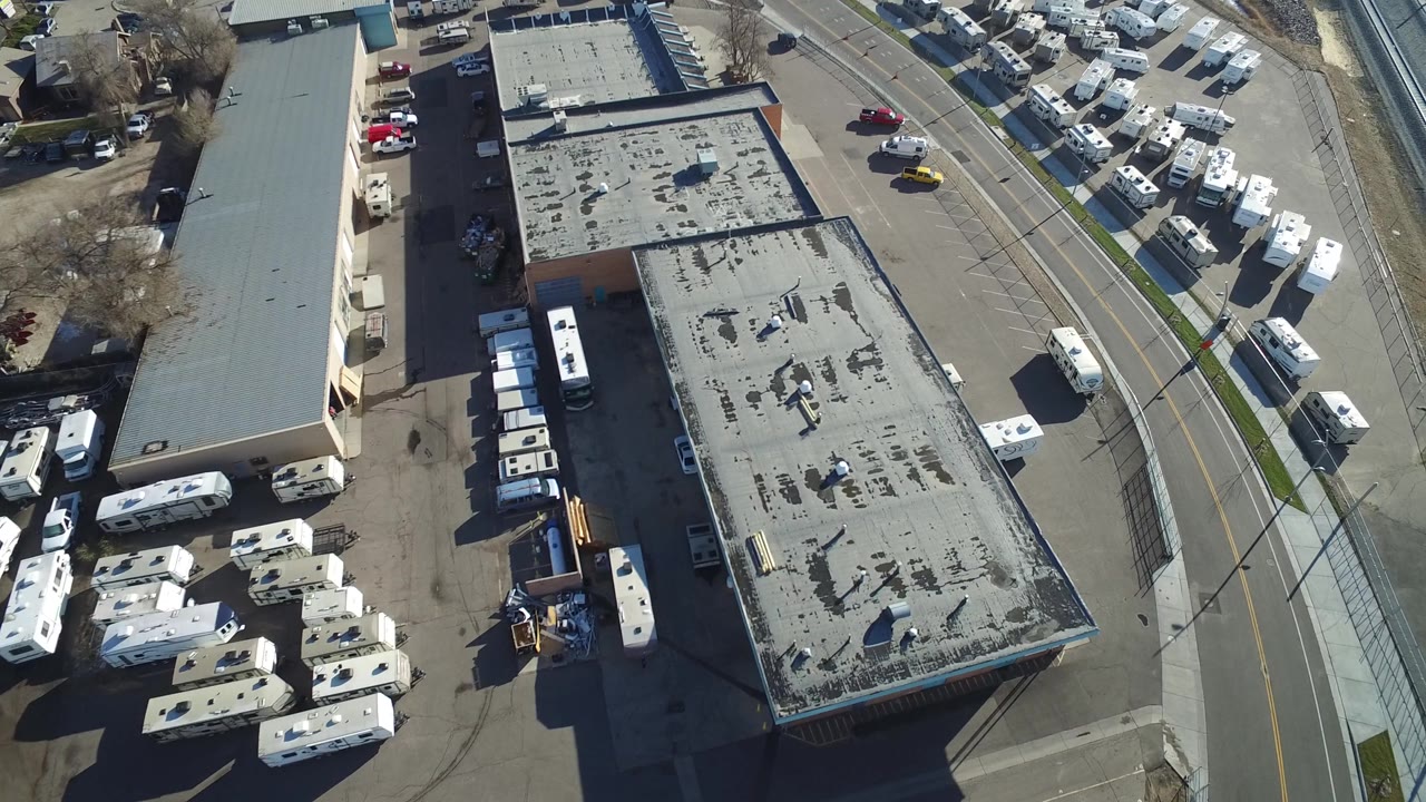 Aerial frame in Hidden Lake, Colorado with a long flat-roof building, RVs parked along both sides, a curved road, and no visible people.