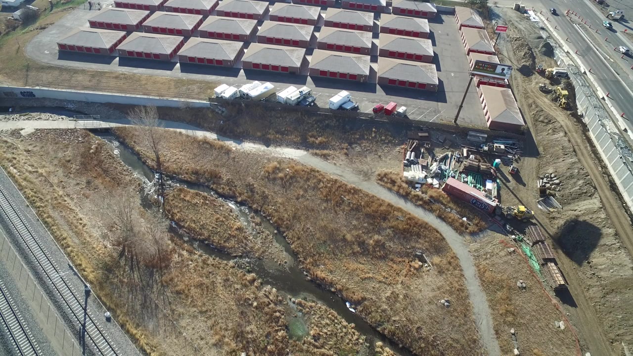 Aerial view of storage buildings beside rail tracks and dry open land.