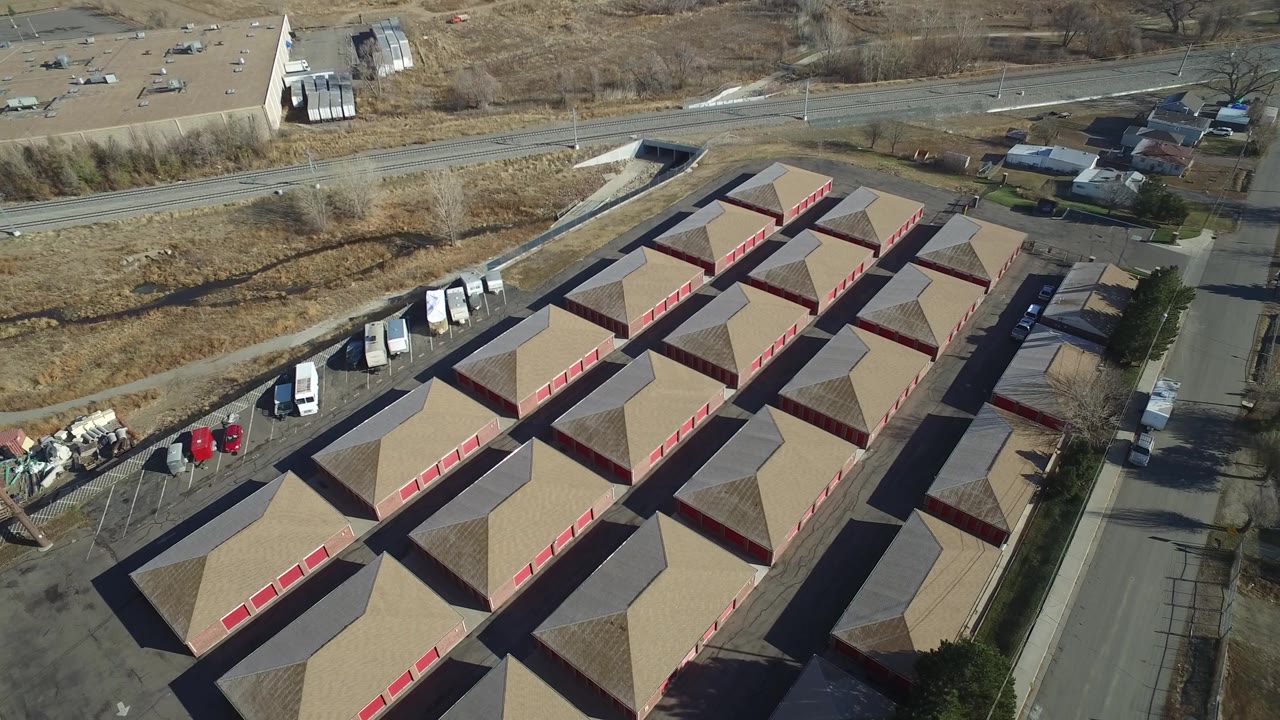 Aerial view in Hidden Lake, Colorado, with repeating tan roofs and red doors filling the lower frame, a road corridor and open brown ground beyond, and no visible people.