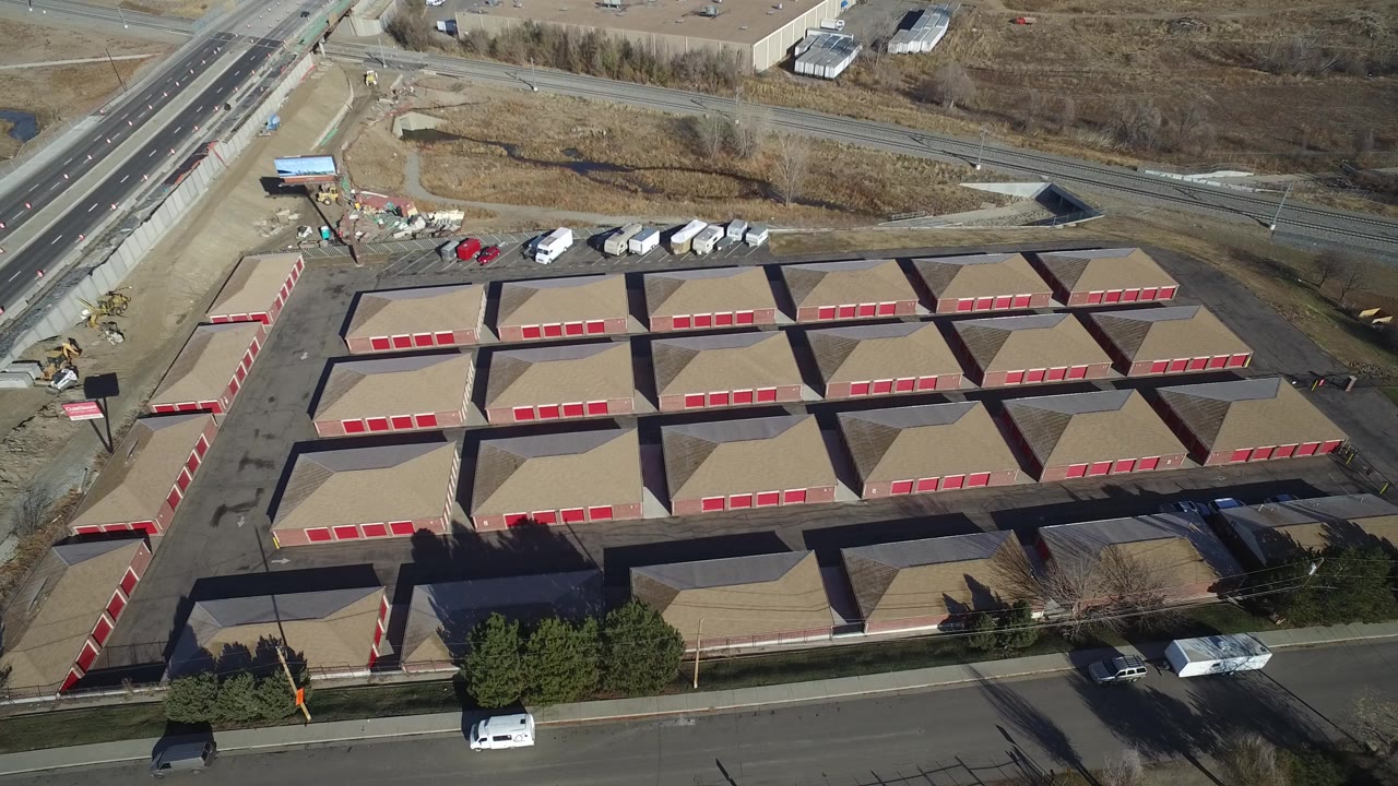 Aerial view of tan storage-like buildings with red doors beside roads.