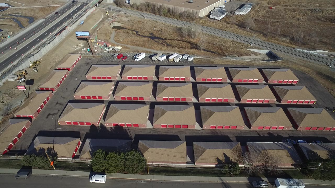 Aerial view of tan storage buildings with red doors beside roads and dry open land.